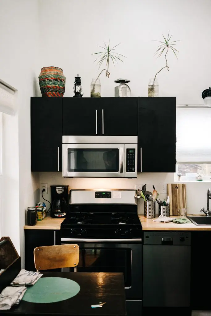 Oats Clean stainless steel microwave and stovetop inside a modern kitchen design.