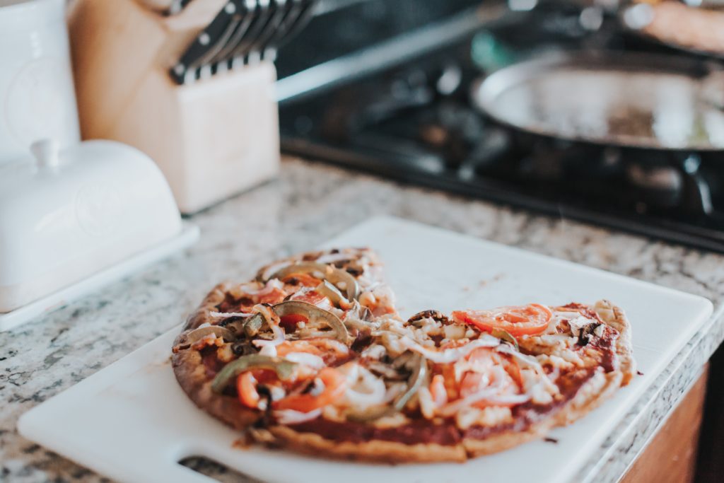 Half eaten pizza that is topped with roasted tomato and sliced bell peppers