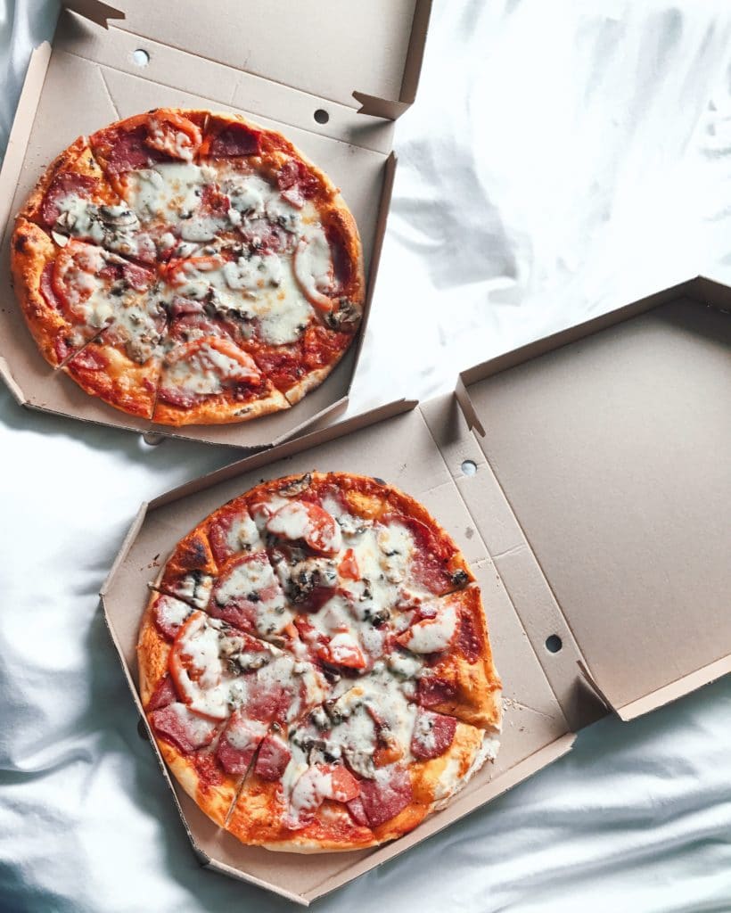 Two whole pizzas inside pizza boxes