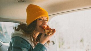 Female sitting inside a car eating cold pizza