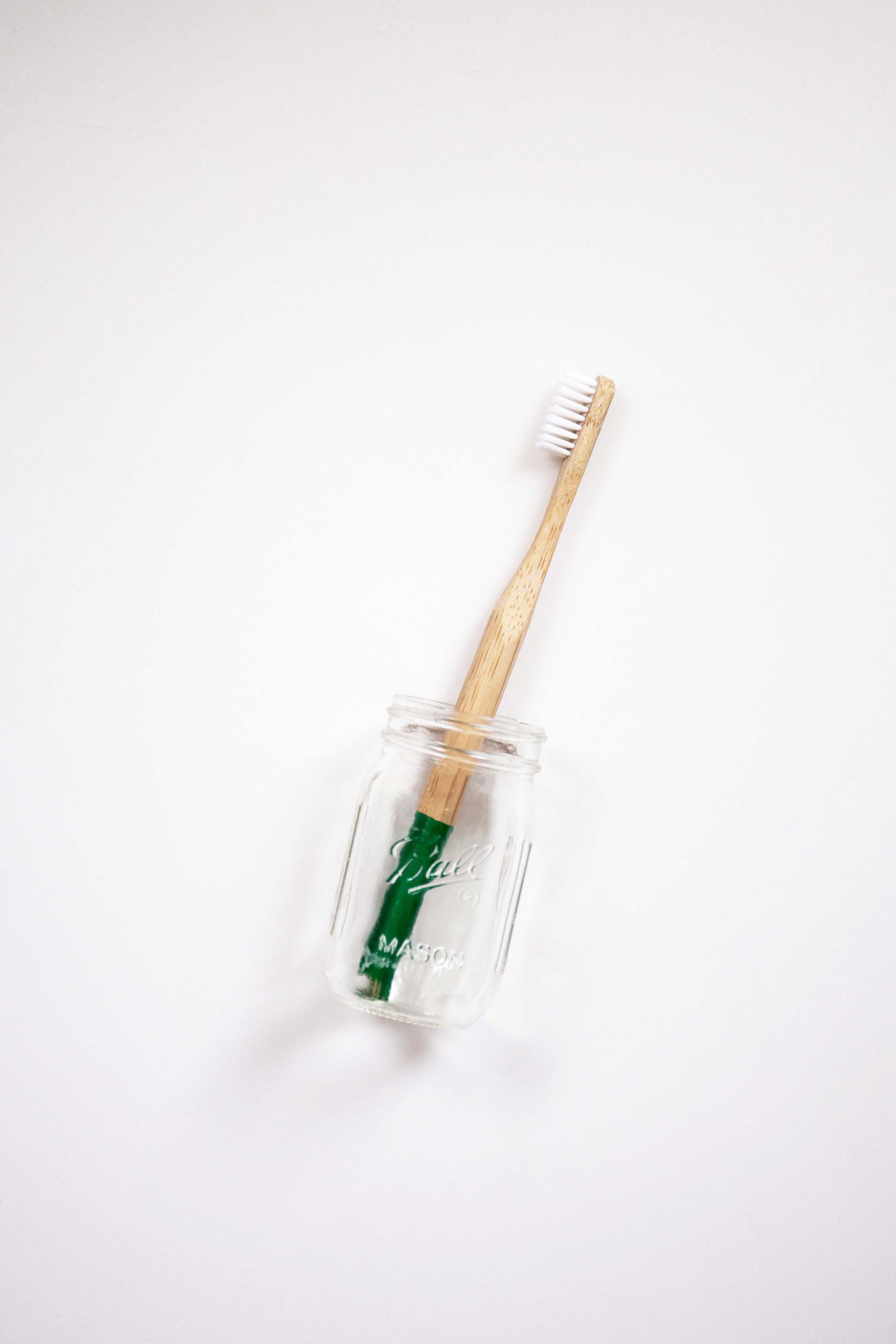 Toothbrush and homemade microwave cleaner together in a small glass jar.